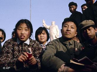 Chinese children sit holding their Little Red Books of Chairman Mao's quotations in Shanghai, date unknown.  In the background is a statue of Mao. (AP Photo)